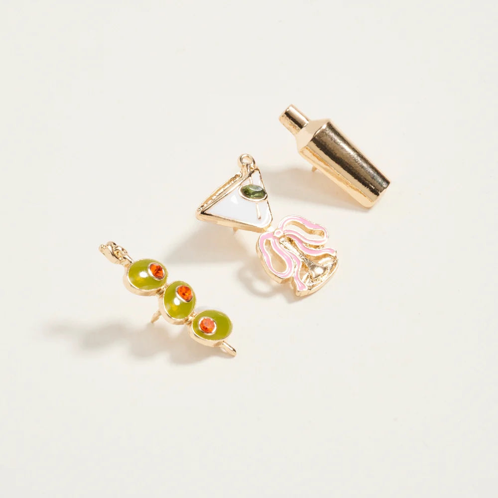 Two gold earrings with green and red gemstones on a light gray background