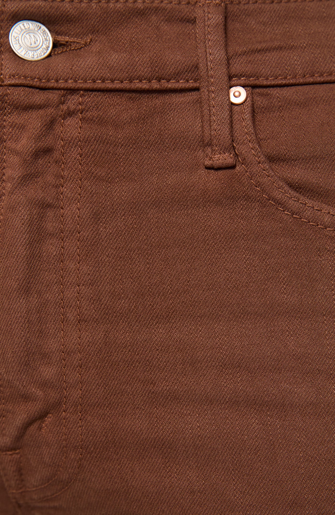 Close-up of brown denim pants showing the waistband, button, rivet, and front pocket stitching.