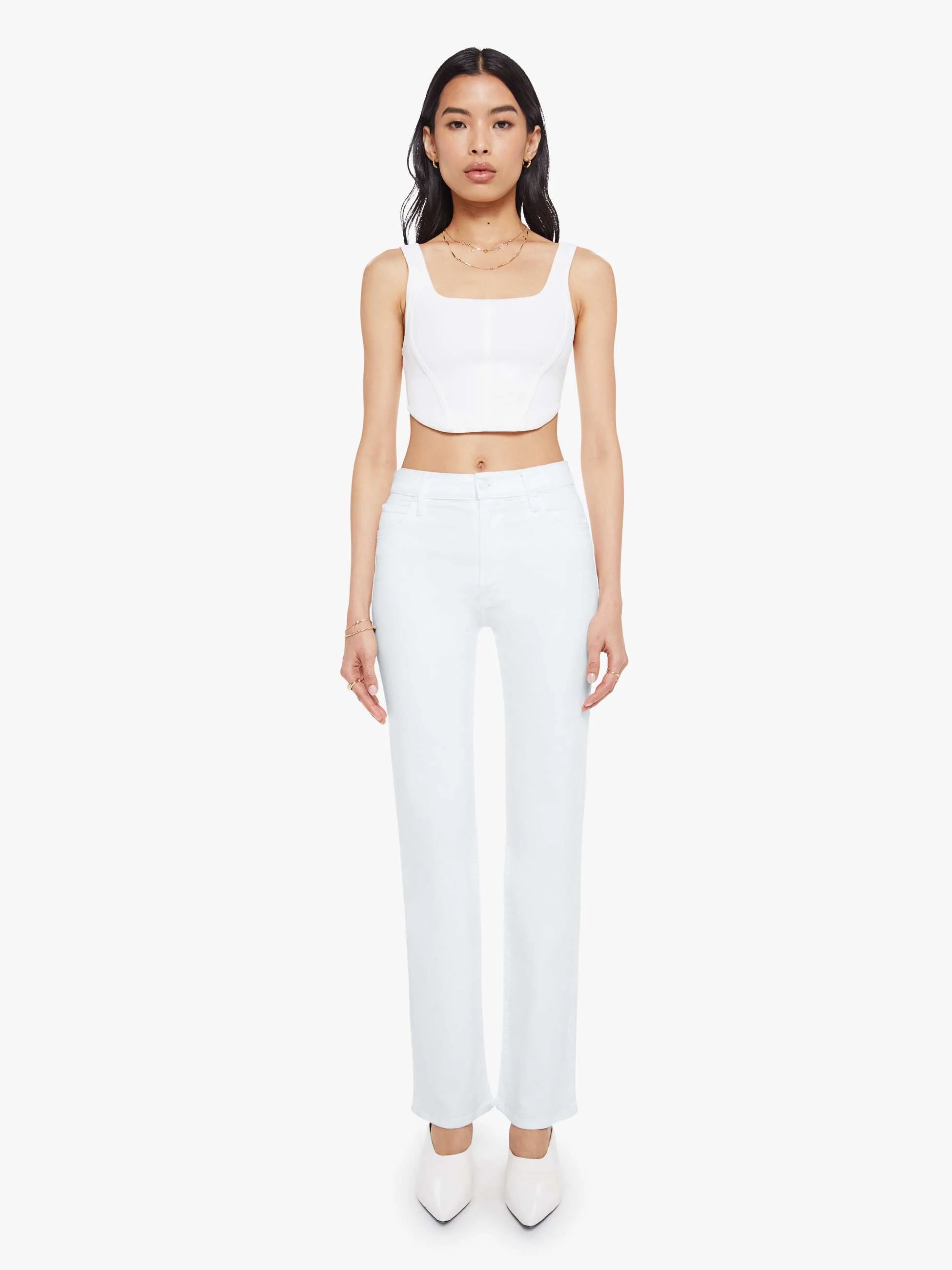 Woman wearing a white sleeveless top and pants on a white background