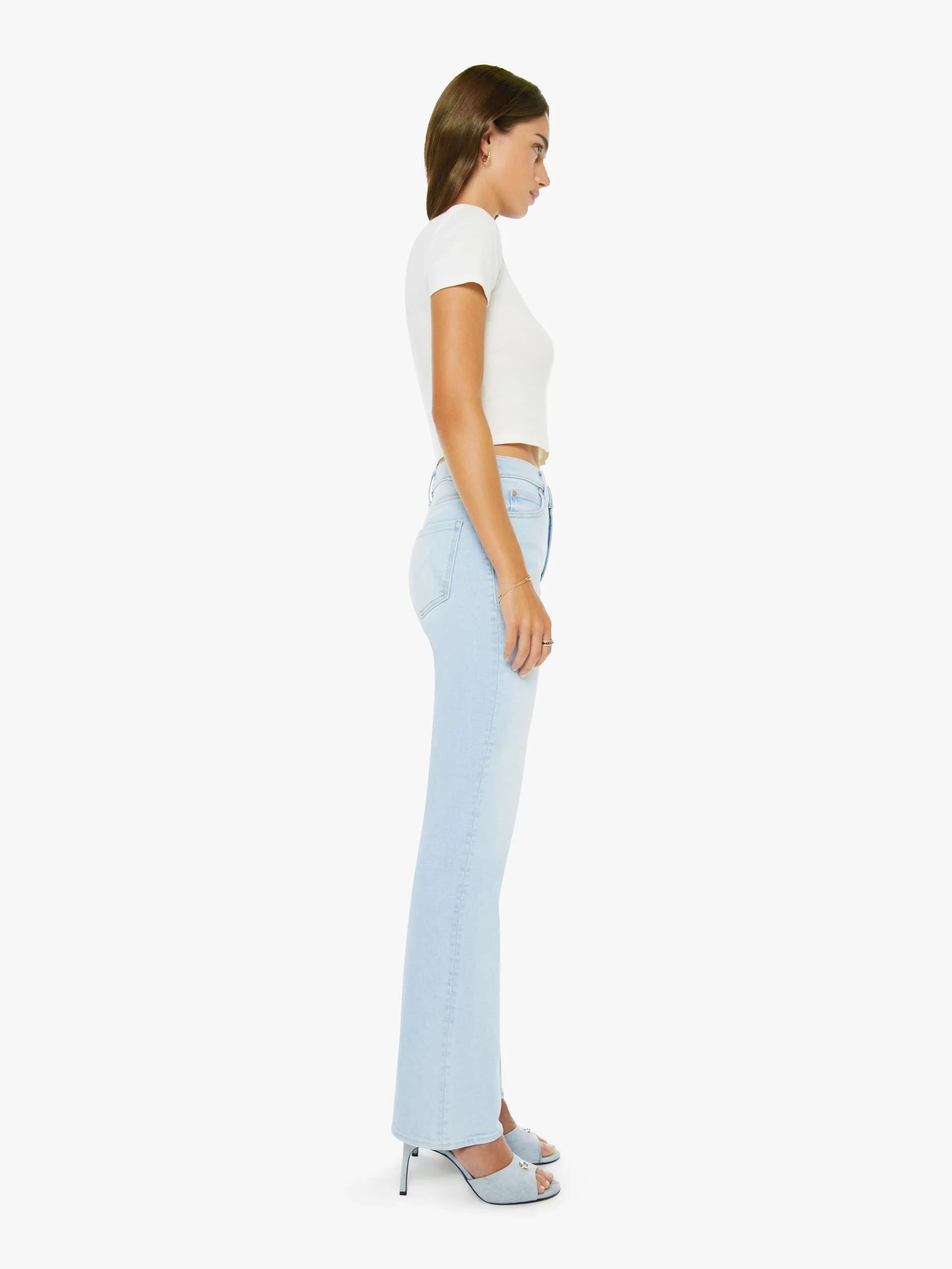 Woman wearing light blue jeans and a white top on a white background