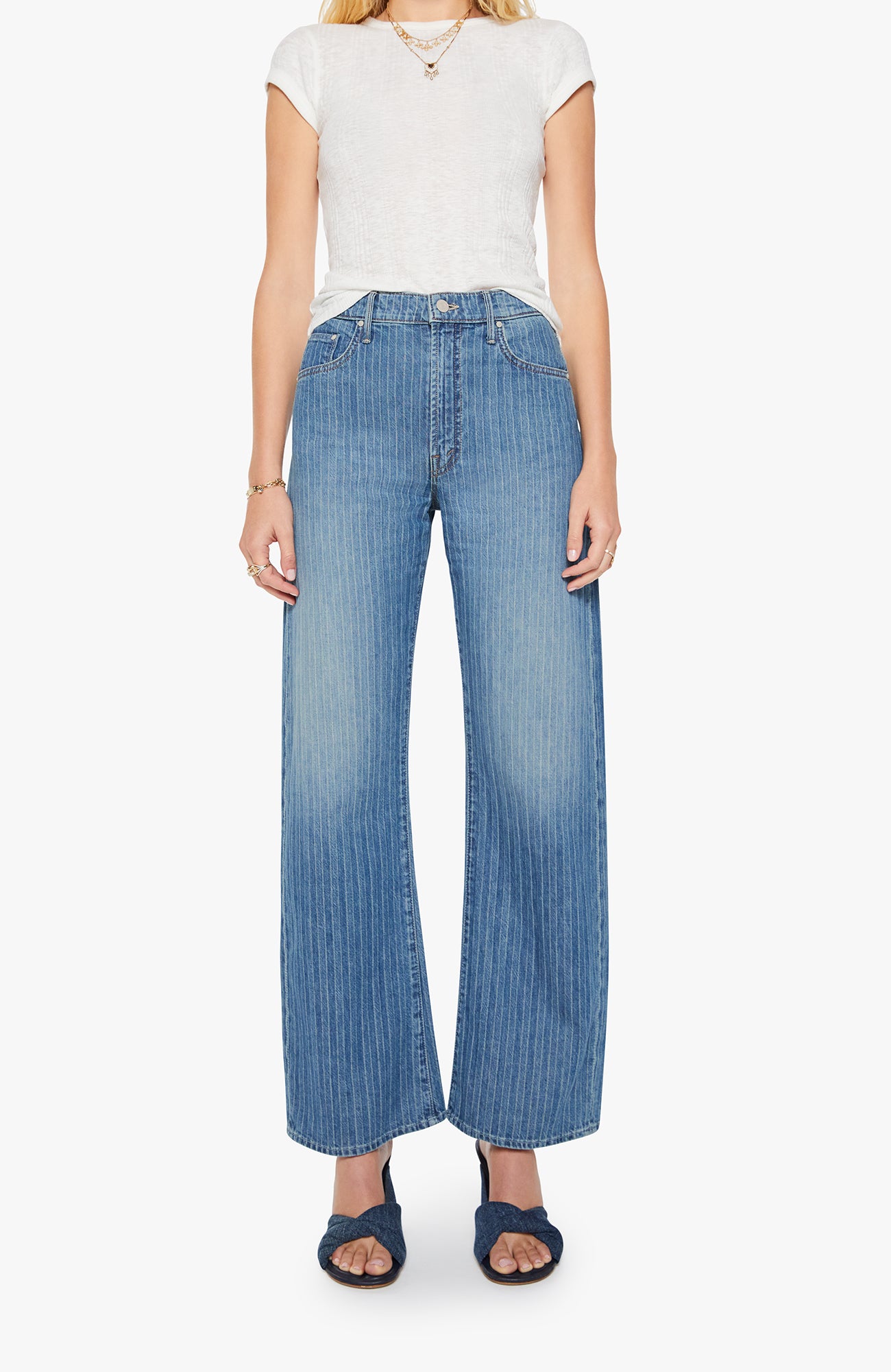 Woman wearing blue wide-leg jeans and a white top on a white background