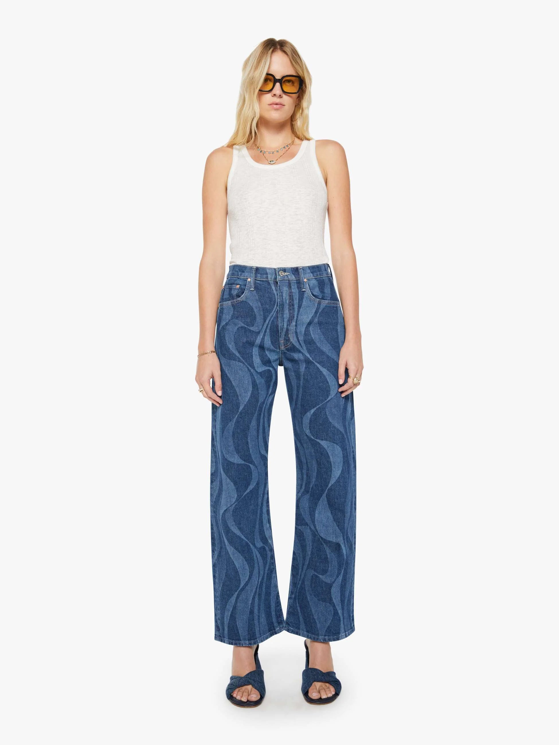 Woman wearing blue patterned jeans and a white top on a white background