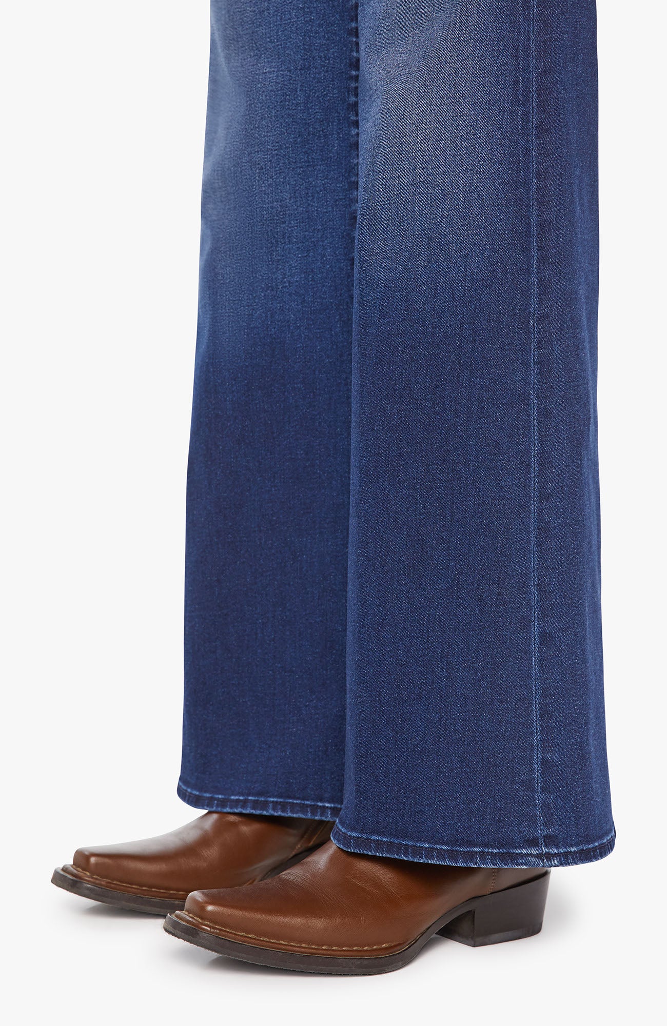 Blue jeans worn with brown leather boots on a white background