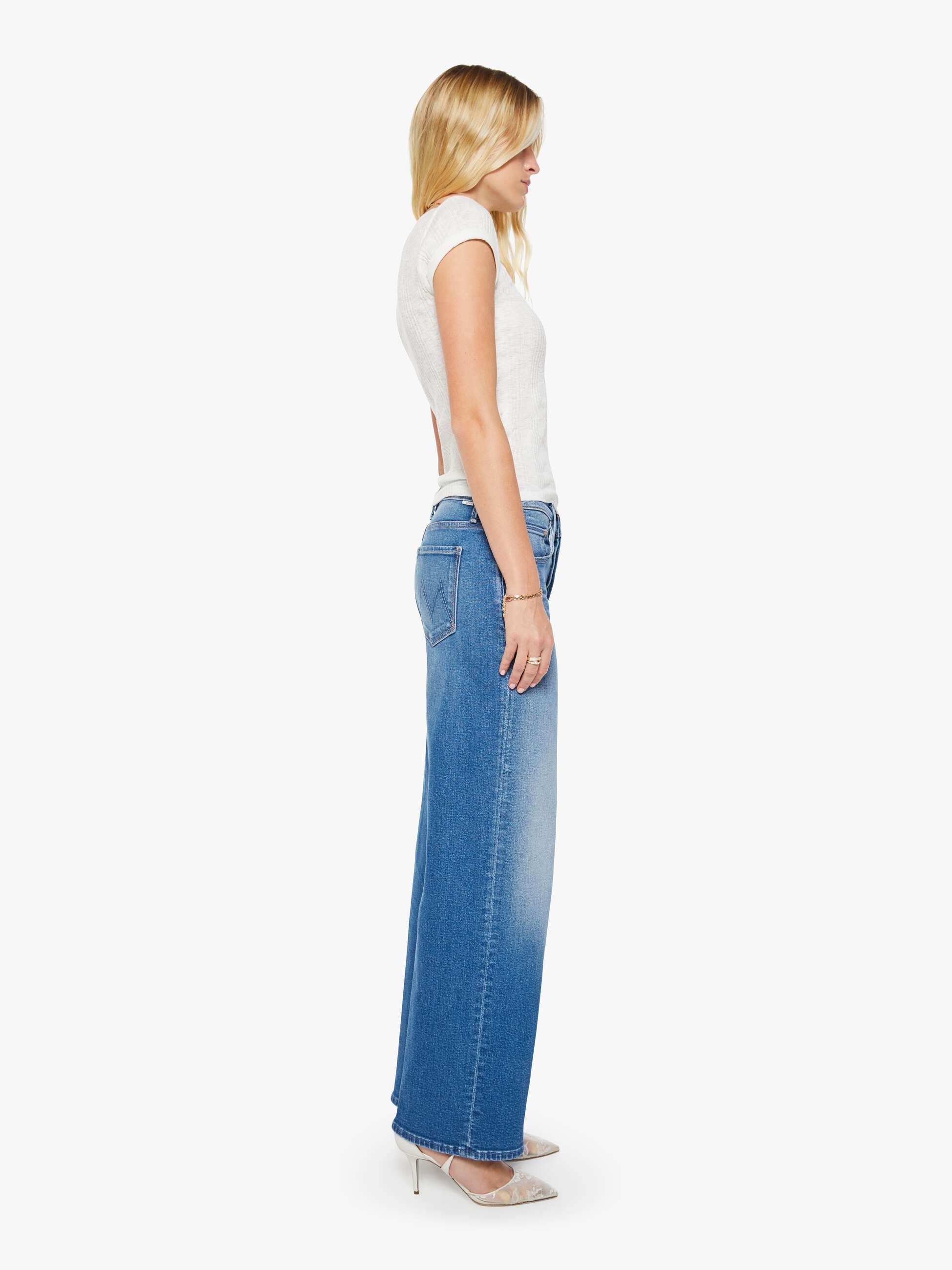 Woman wearing a white top and blue jeans on a white background