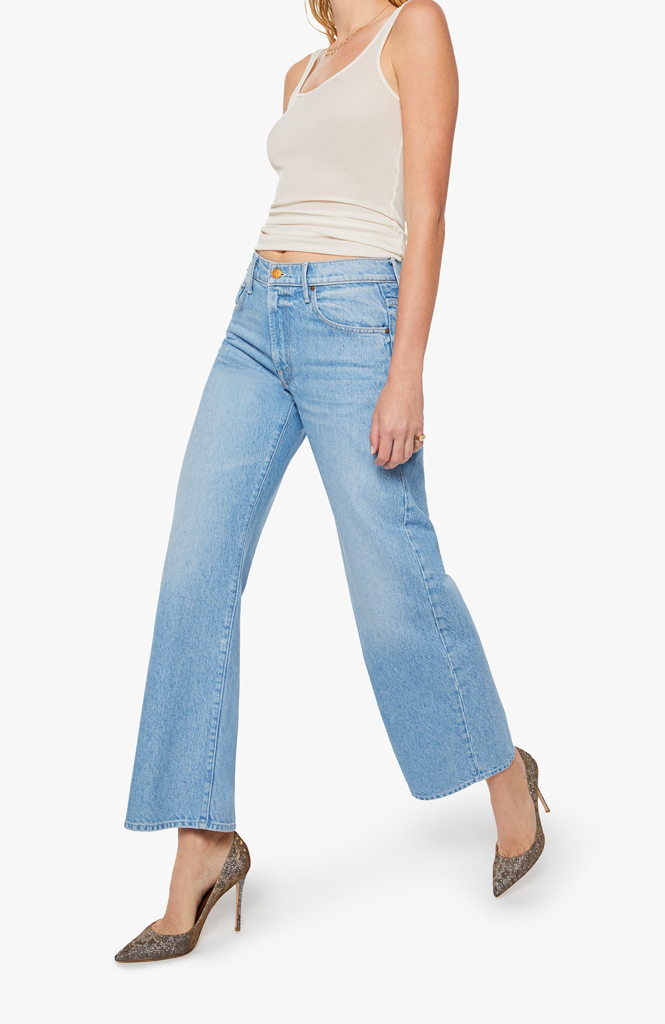 Woman wearing light blue jeans and a beige top on a white background