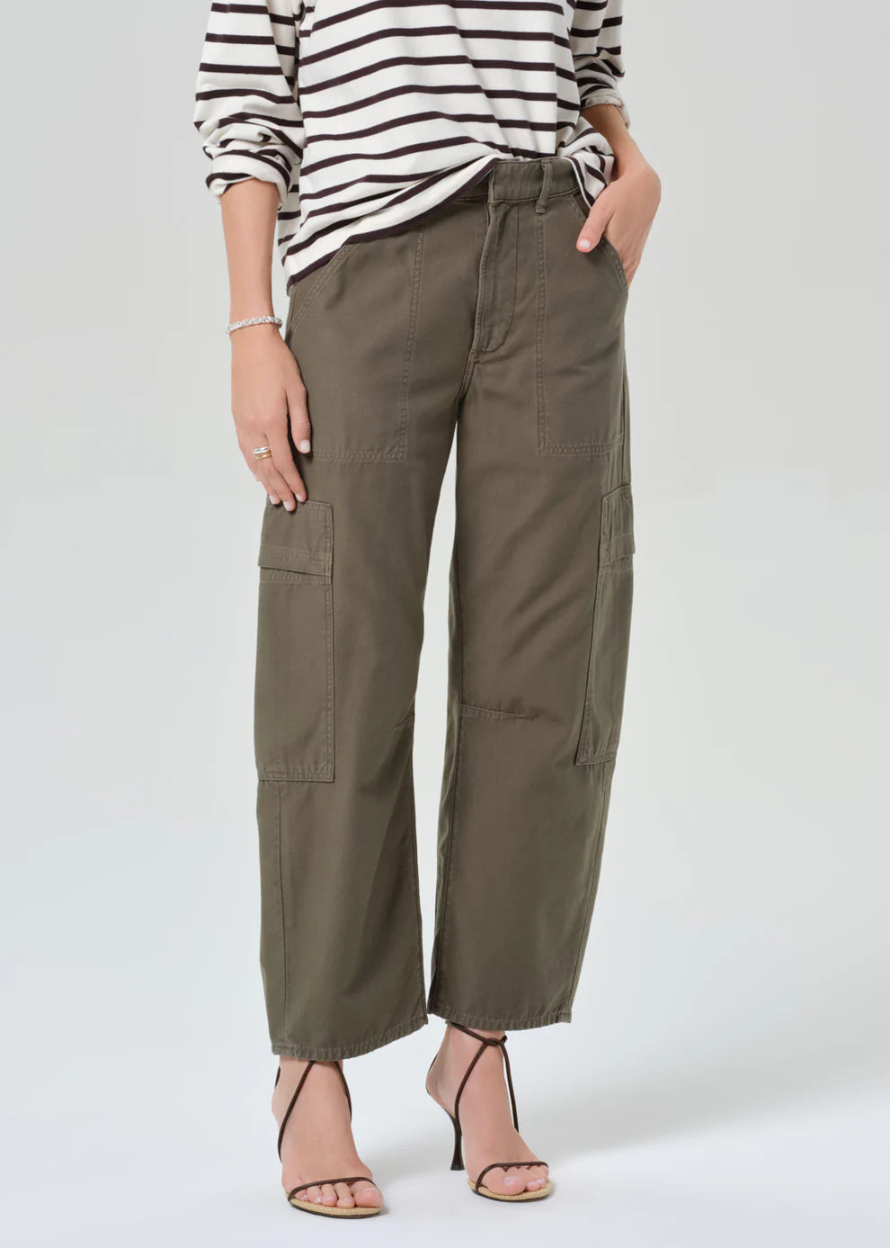 Person wearing olive green cargo pants and a striped shirt on a white background