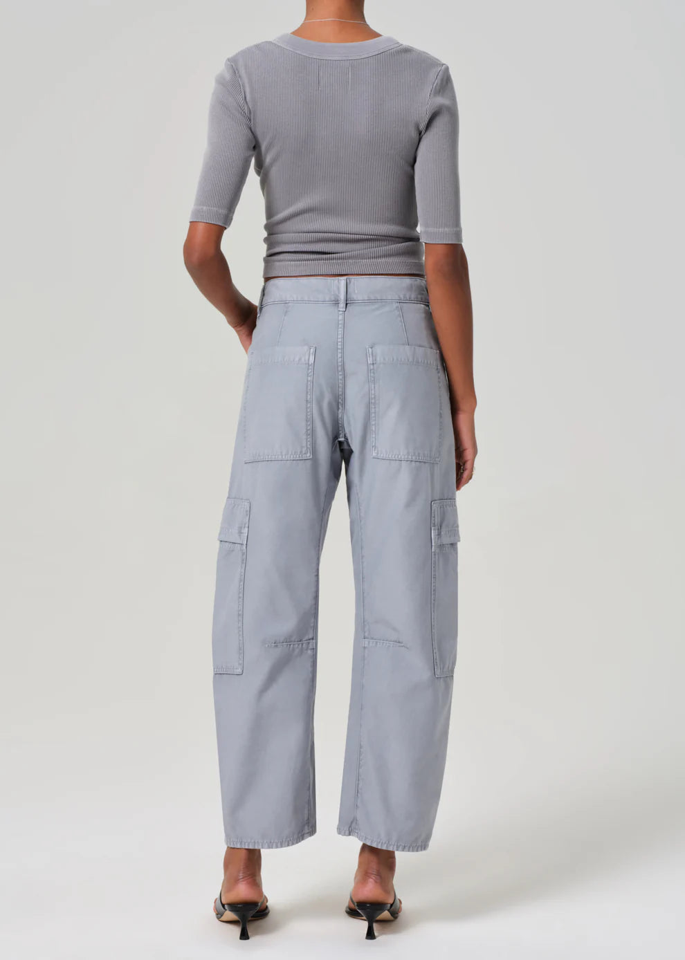 Person wearing a gray outfit with wide-leg pants on a white background