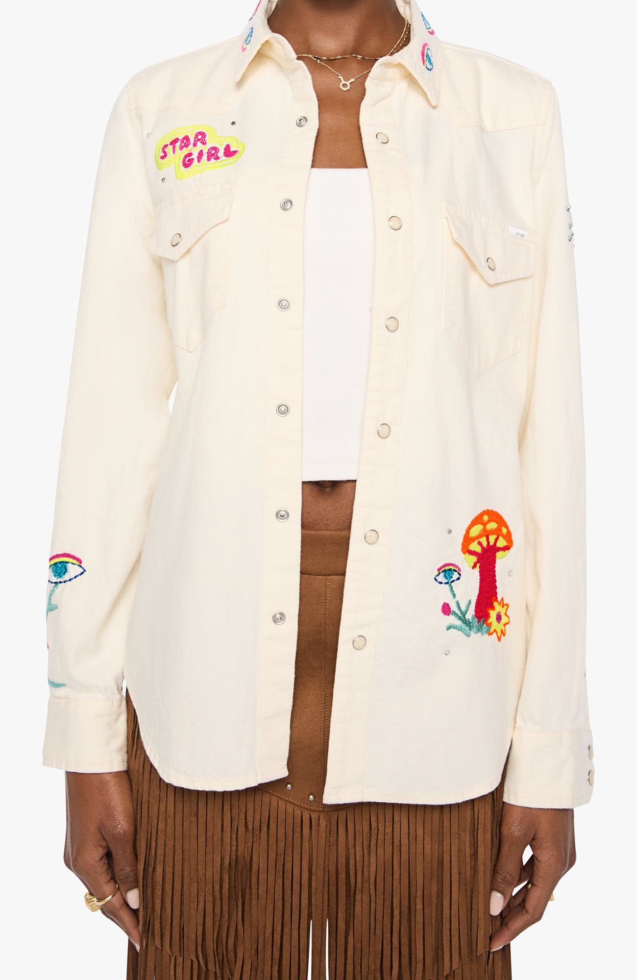 An off-white button-up shirt with colorful embroidered details, including a 'Star Girl' patch on the left chest and a mushroom design on the lower right front, worn by a model.