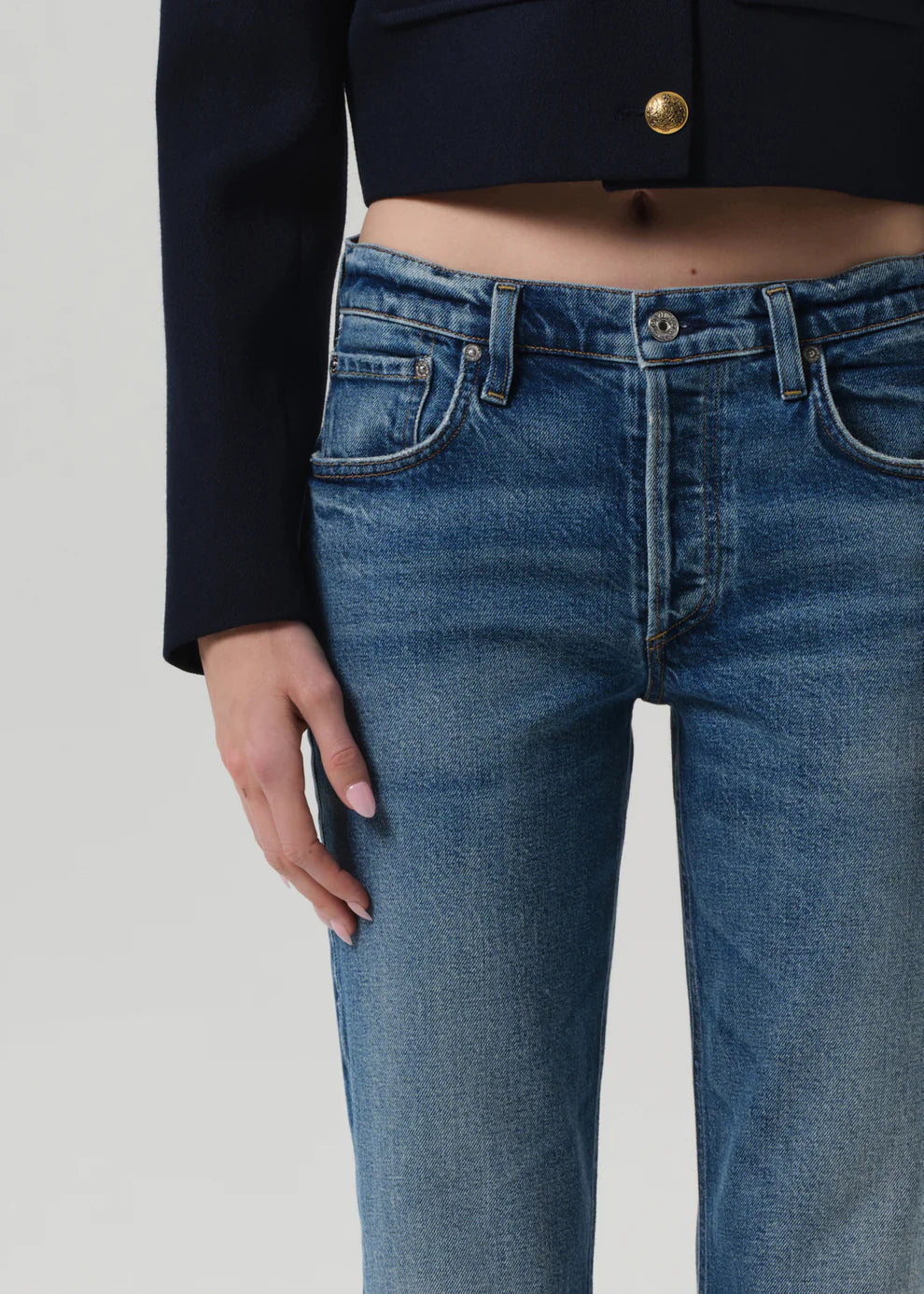 Person wearing blue jeans with a plain background