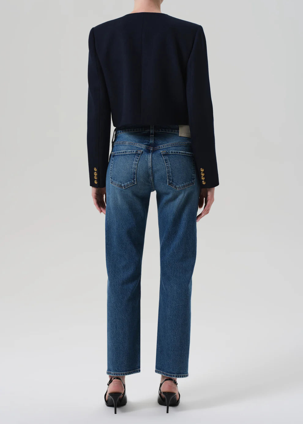 Person wearing a black sweater and blue jeans on a white background