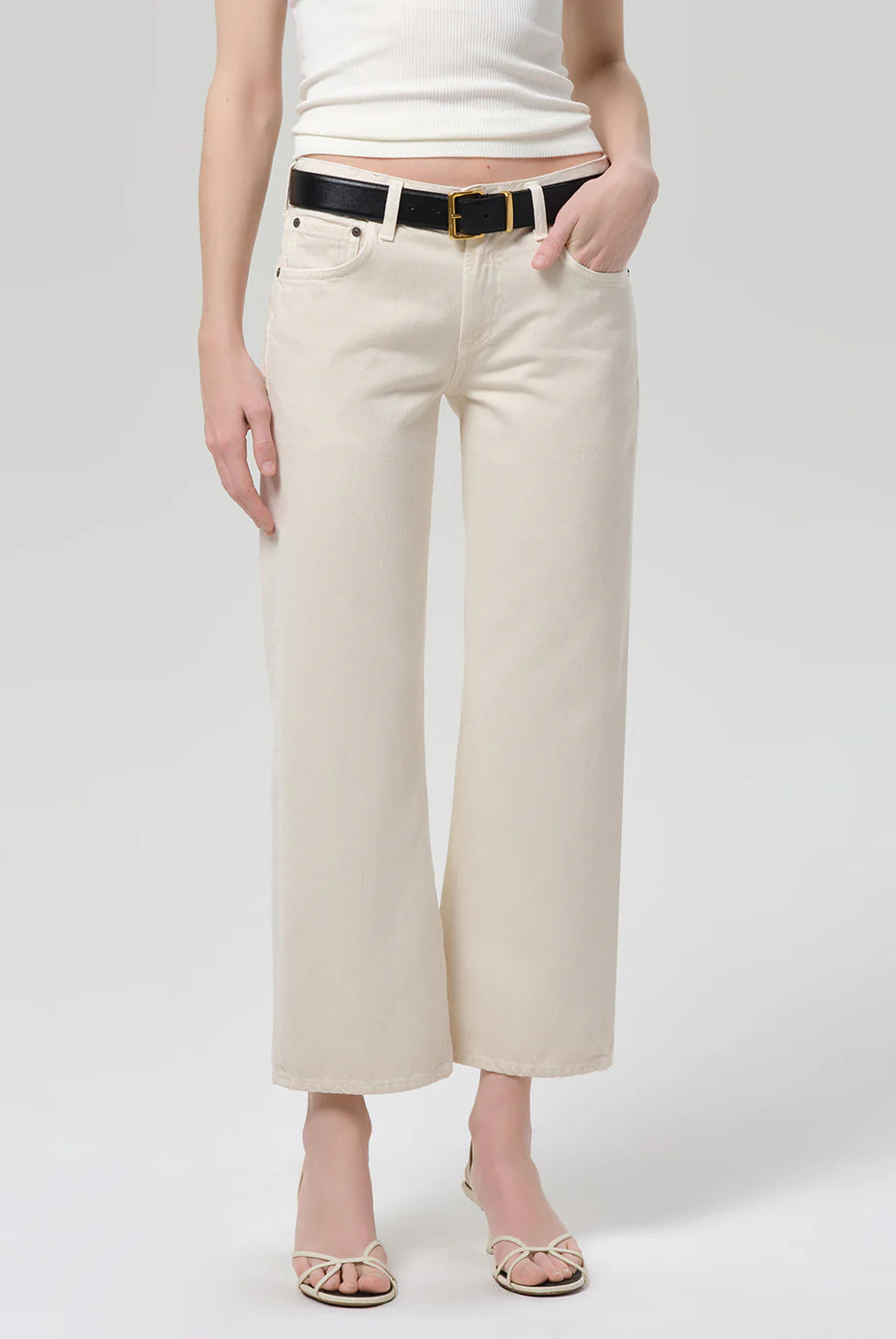 Person wearing beige wide-leg pants with a white top on a plain background