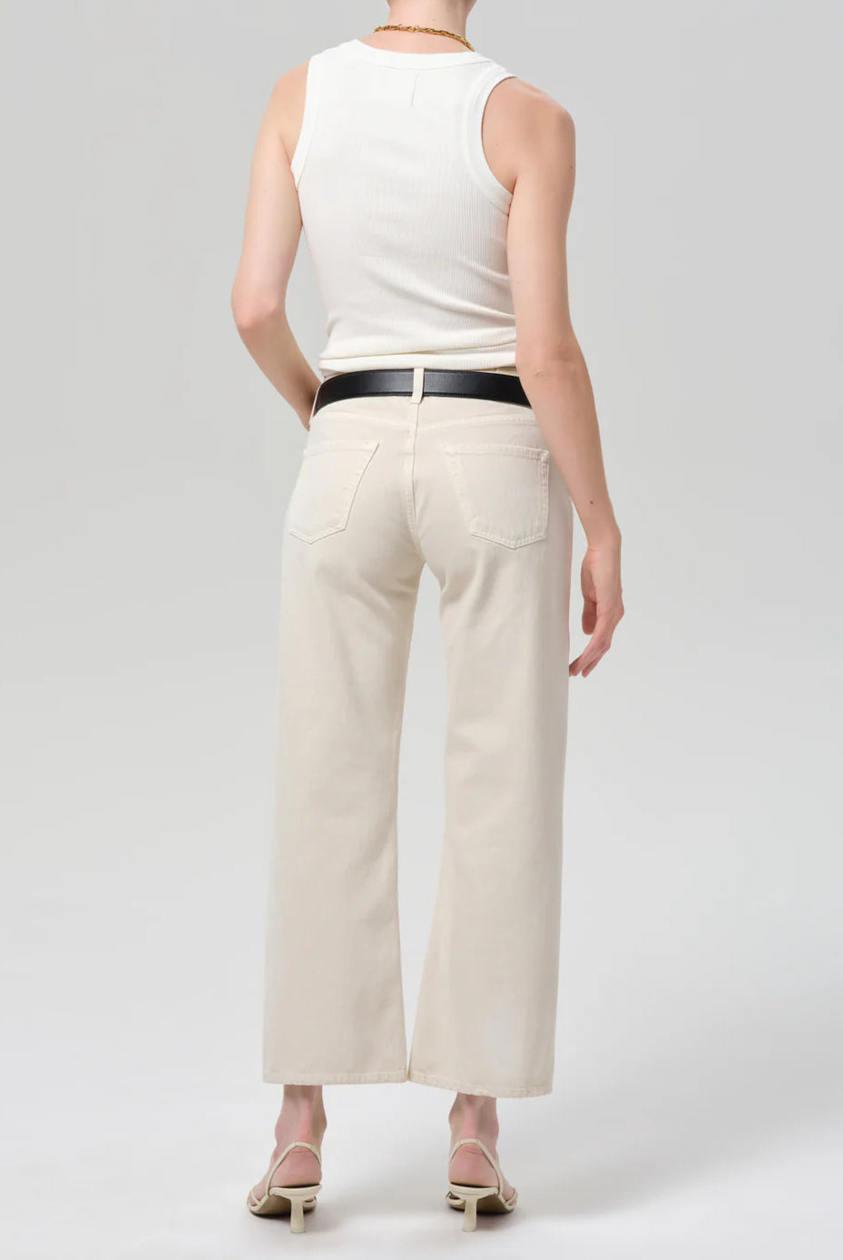 Person wearing a white sleeveless top and beige wide-leg pants on a light gray background