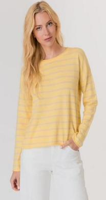 Woman wearing a yellow striped sweater and white pants on a plain background
