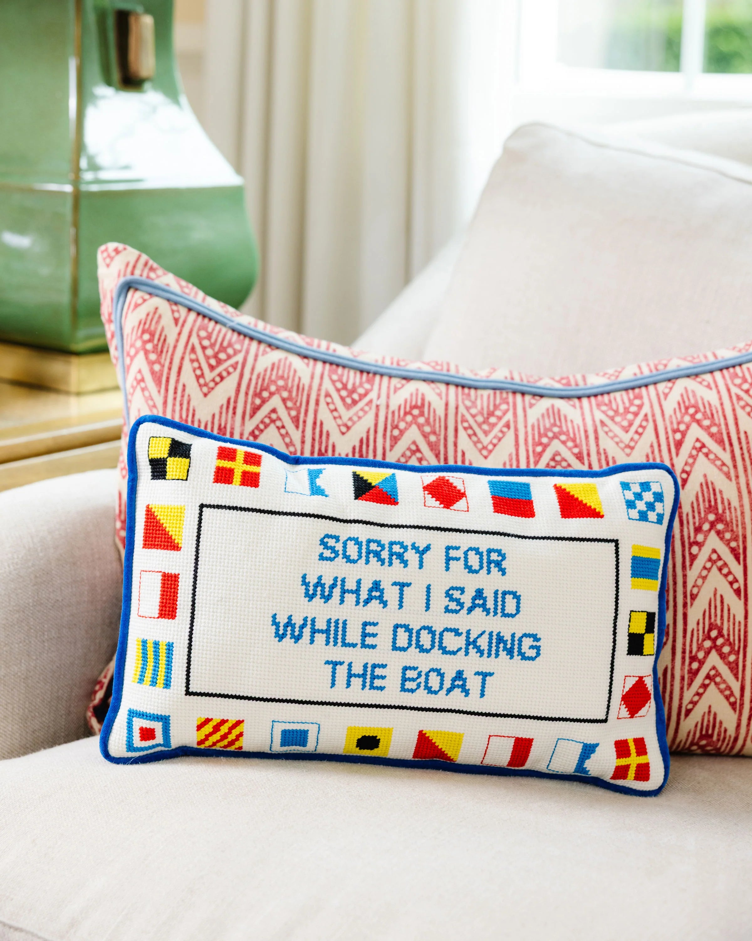 Decorative pillow with nautical flags and text on a couch