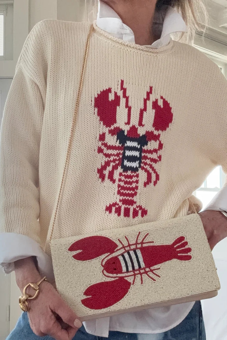 Person wearing a sweater with a lobster design, holding a matching handbag.