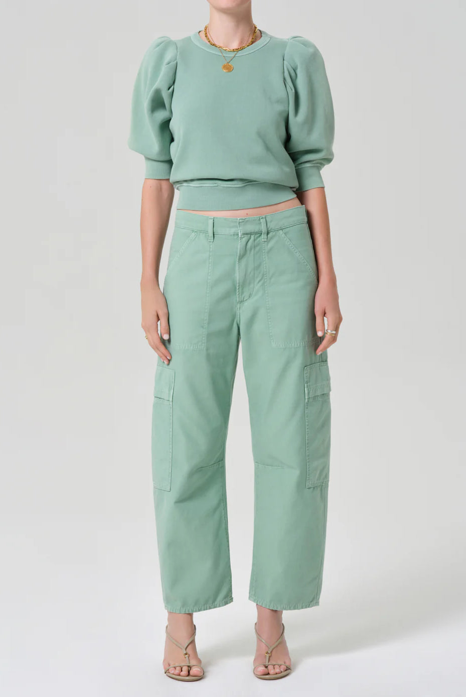 Person wearing a mint green outfit with a top and pants on a white background