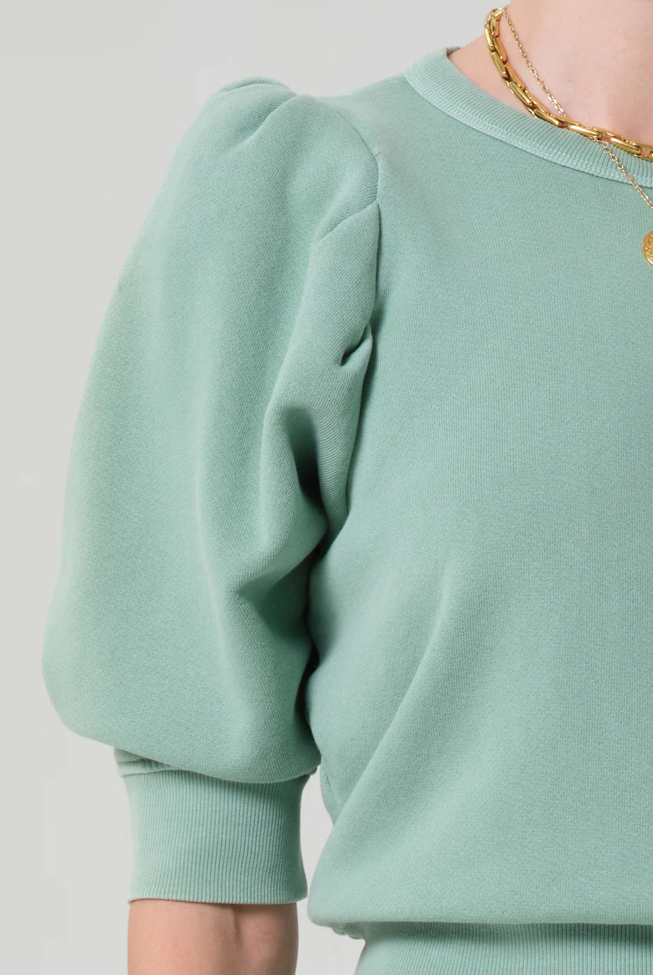 Light green sweatshirt worn by a person on a plain background