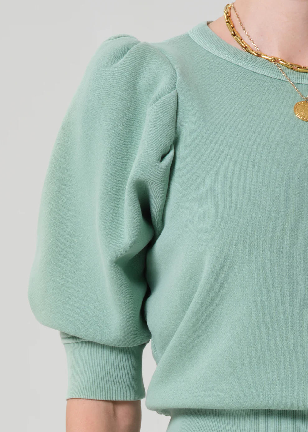 Light green sweatshirt worn by a person on a plain background