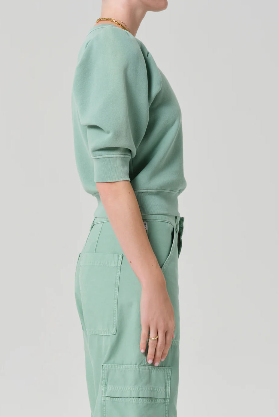 Person wearing a light green outfit on a plain background