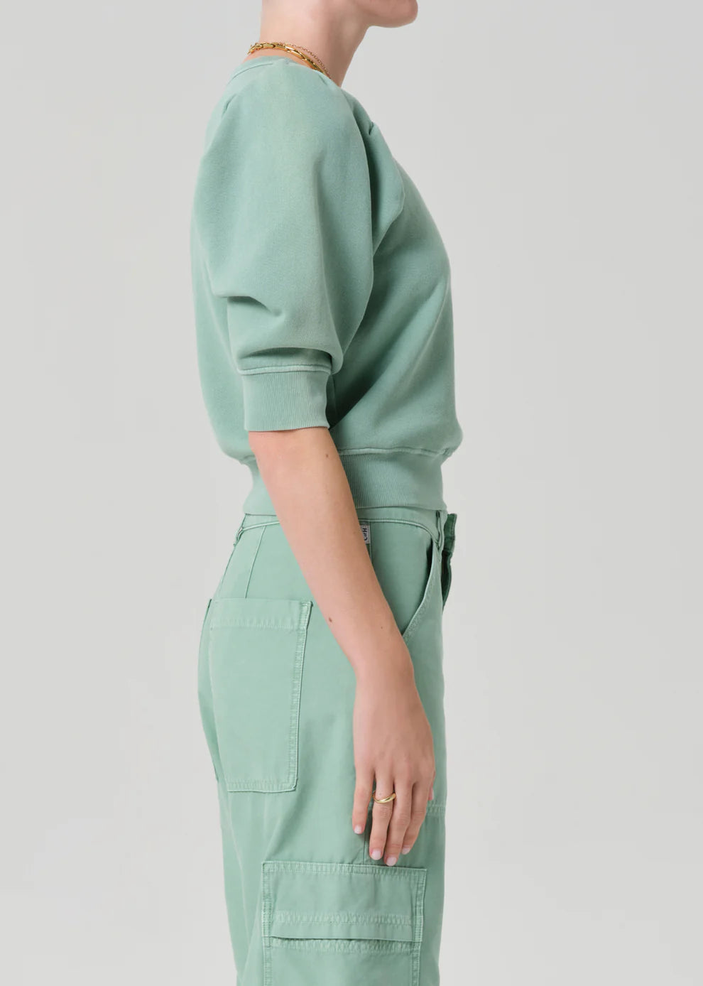 Person wearing a light green outfit on a plain background
