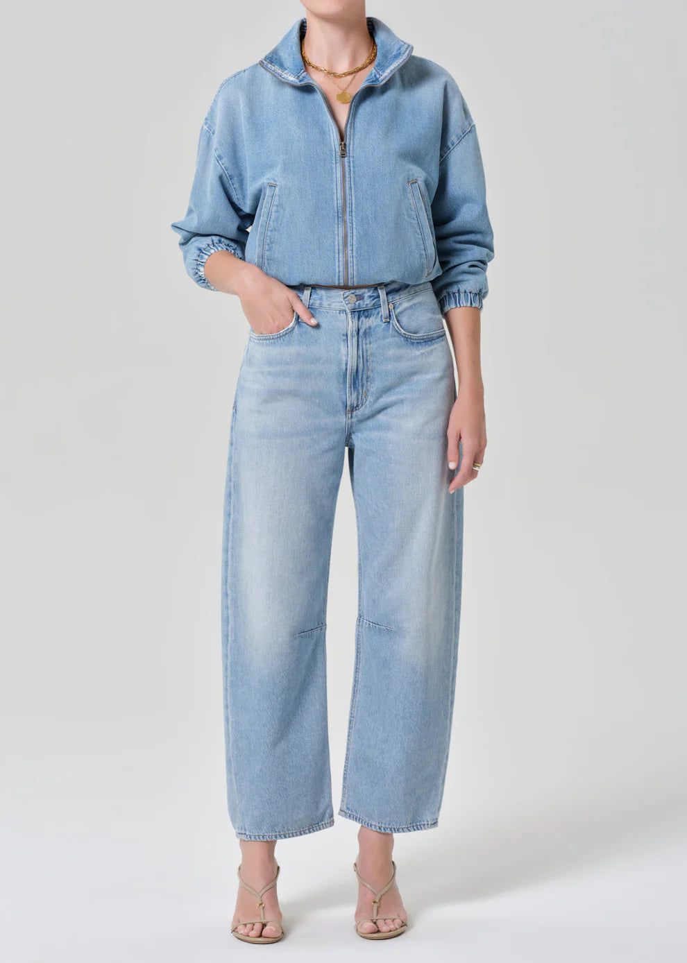 Person wearing a blue denim jacket and jeans on a white background