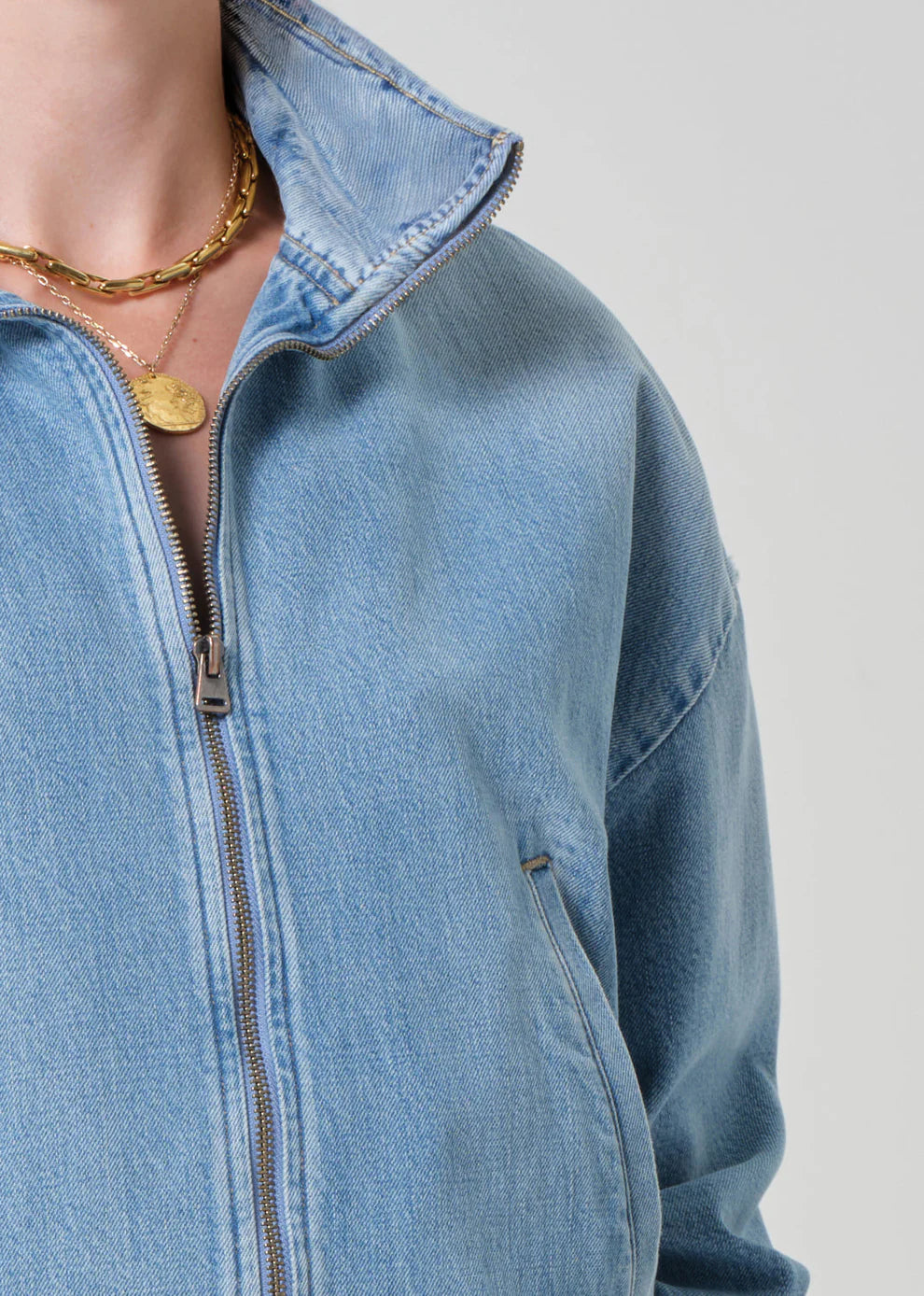 Close-up of a person wearing a blue denim jacket with a plain background