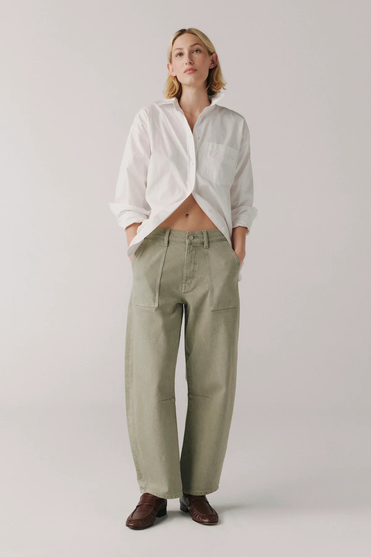 Person wearing a white shirt and green pants on a plain background