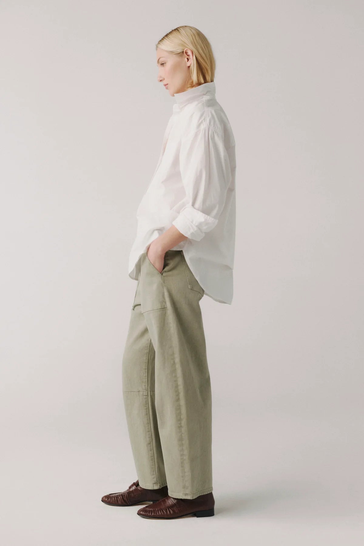 Person wearing a white shirt and beige pants on a plain background