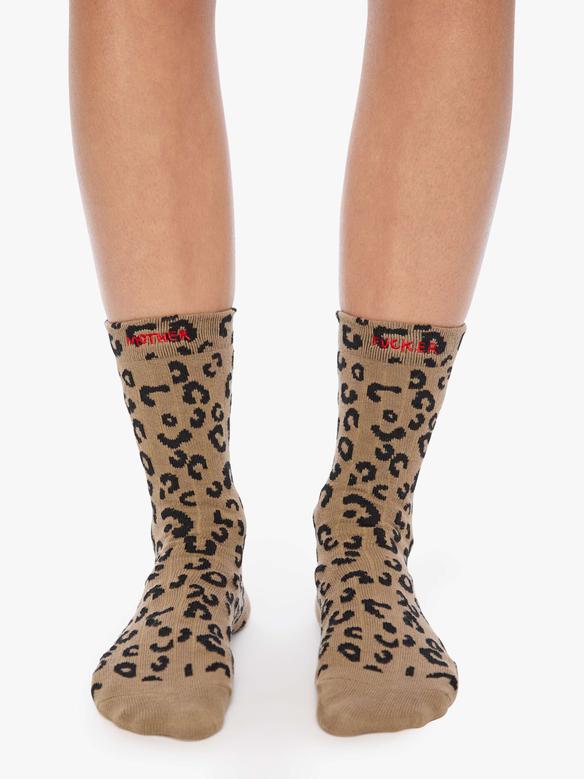 Beige socks with black leopard print pattern worn by a person on a white background