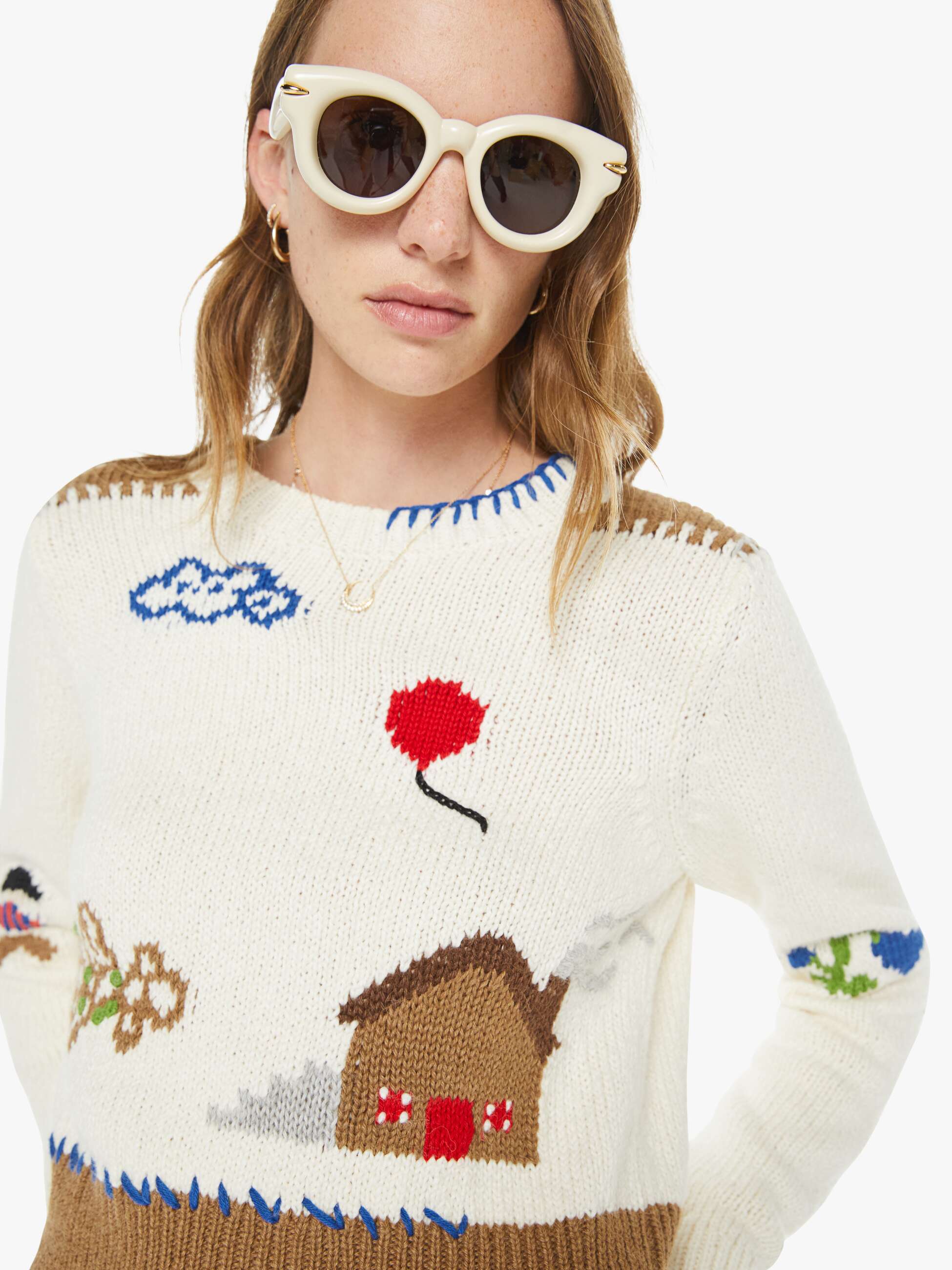 Person wearing a colorful sweater with house design and sunglasses on a white background