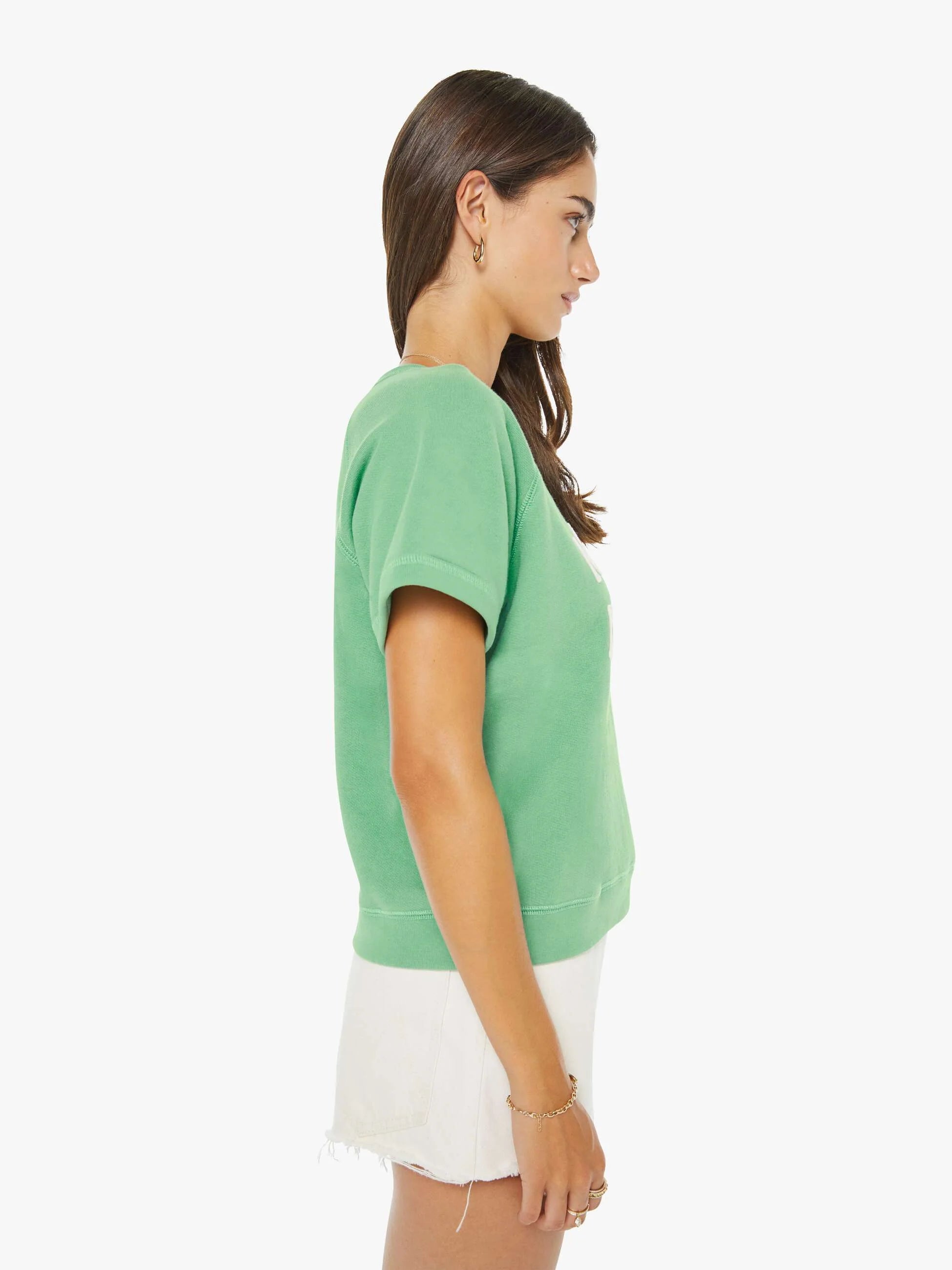 Woman wearing a green top and white shorts on a white background