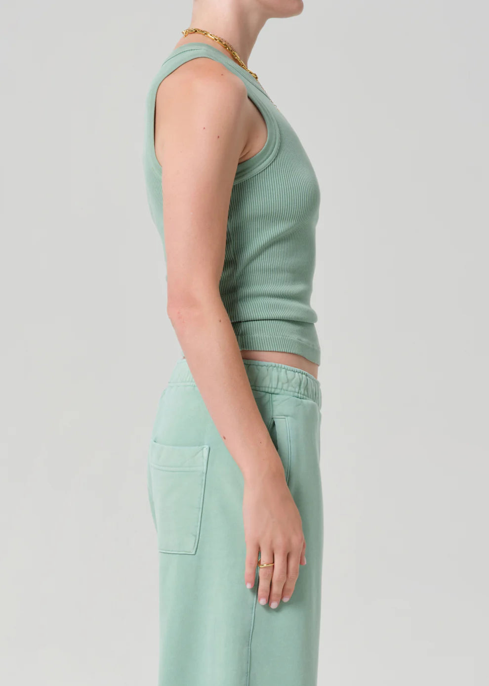 Person wearing a matching mint green tank top and pants on a light gray background