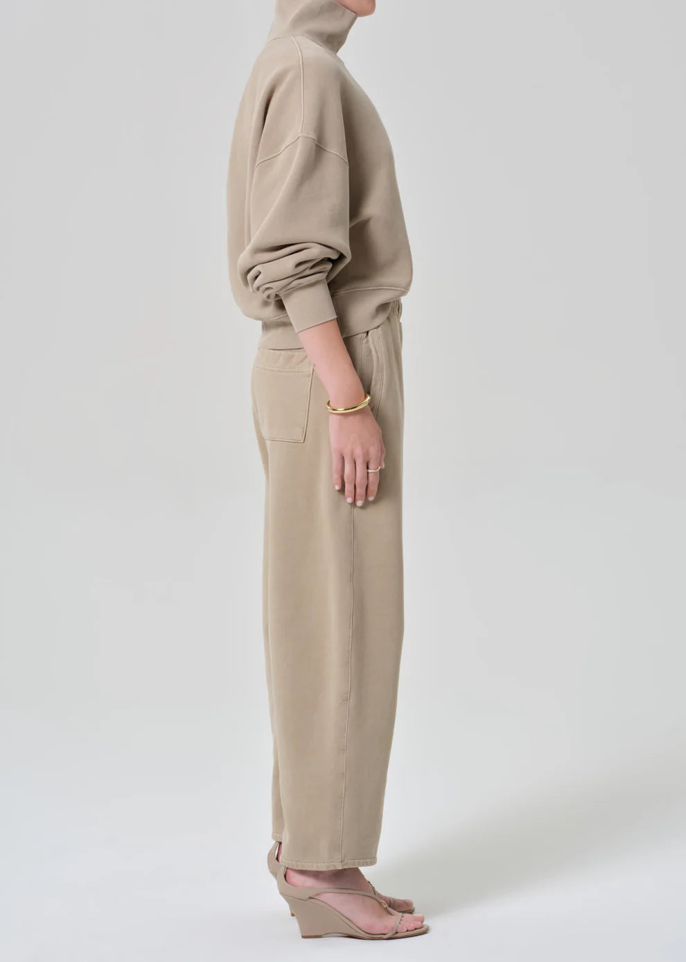 Person wearing a beige hoodie and pants on a white background