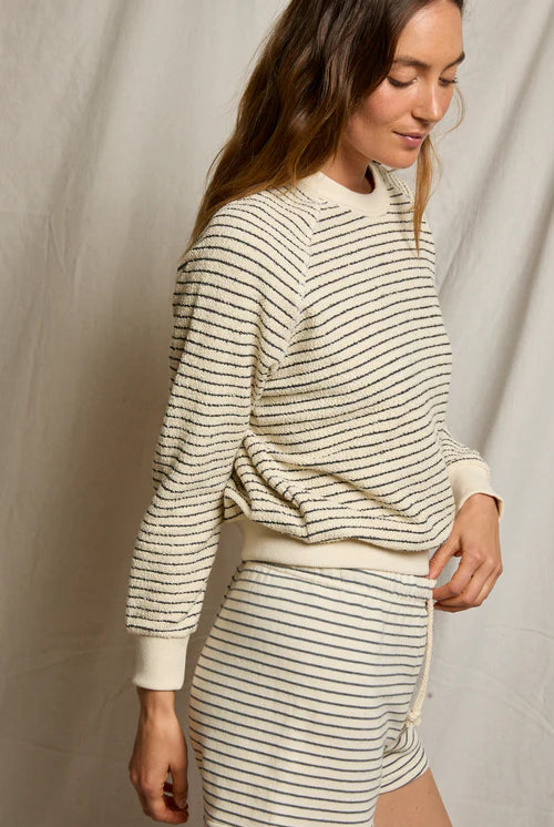 Woman wearing a striped sweater and skirt against a neutral background