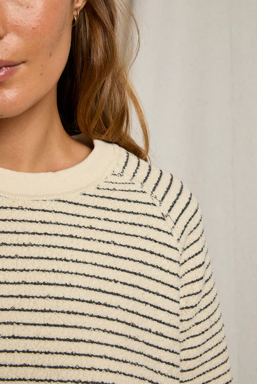 Close-up of a person wearing a striped sweater with a neutral background