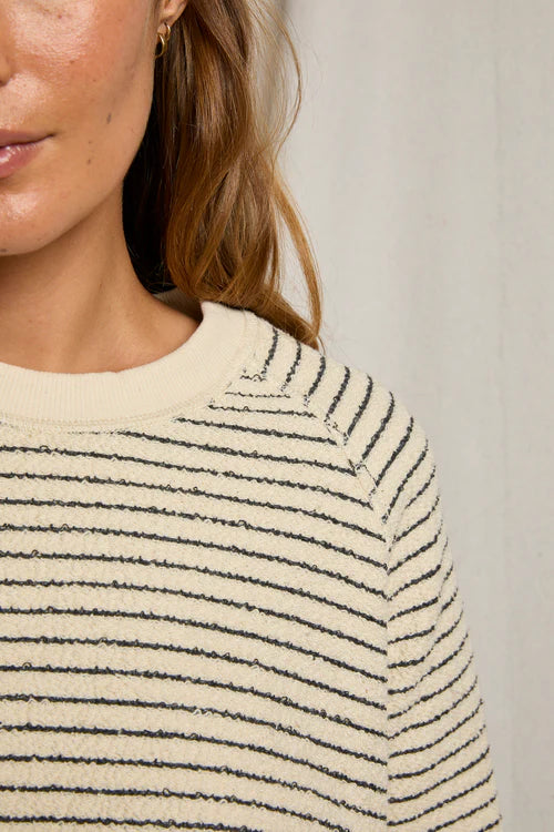Close-up of a person wearing a striped sweater with a neutral background