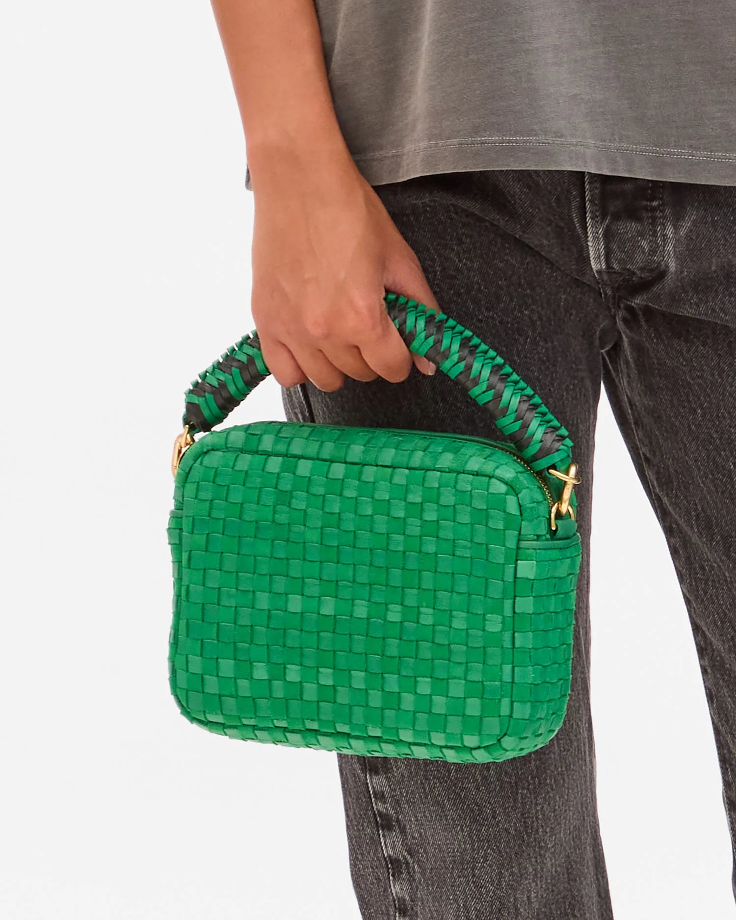 Green woven handbag held by a person against a white background