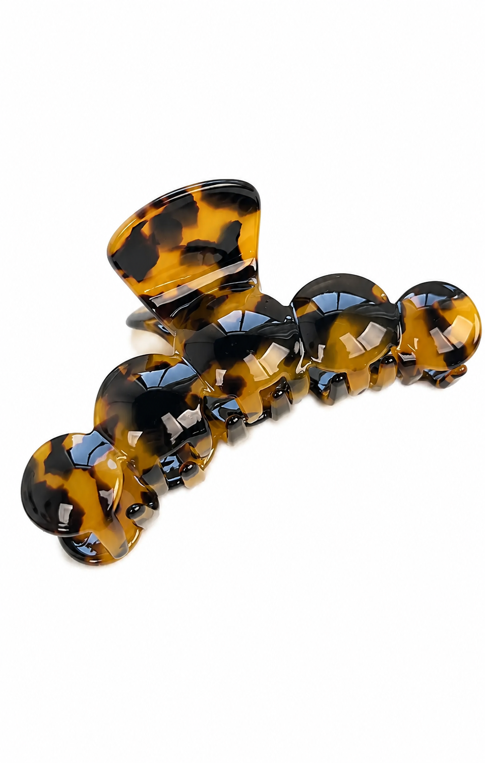 A tortoiseshell hair claw clip with a glossy amber-brown and black pattern, shown on a plain white background.