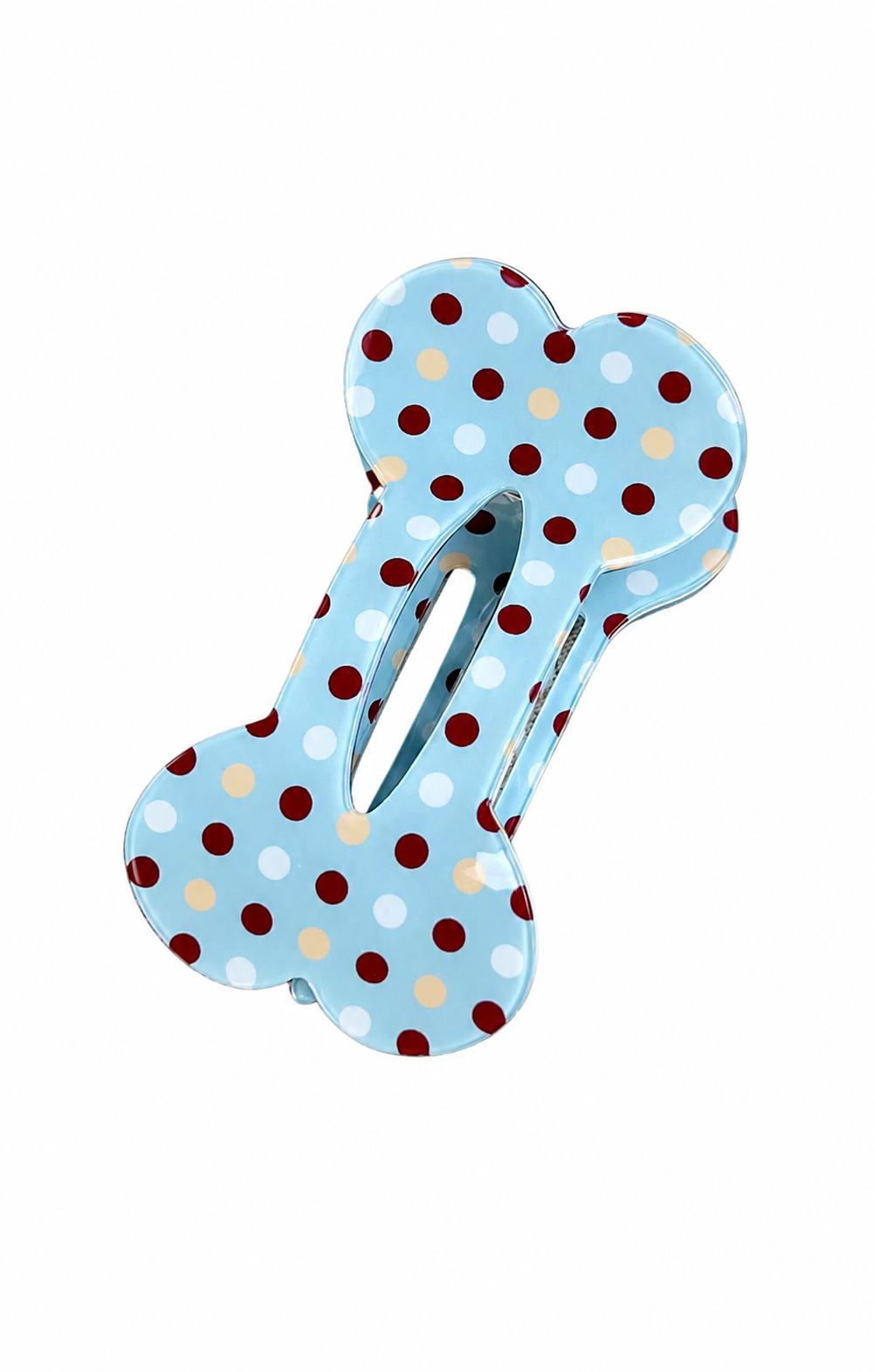 A bone-shaped hair claw clip with a light blue background and a pattern of red, white, and beige polka dots, shown on a plain white background.