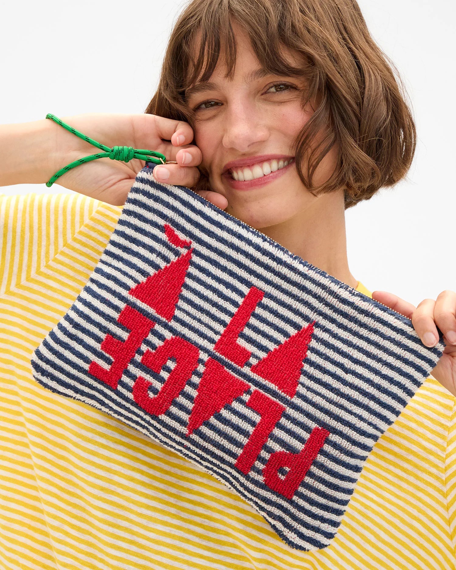 Woman holding a striped pouch with red text and sailboat design