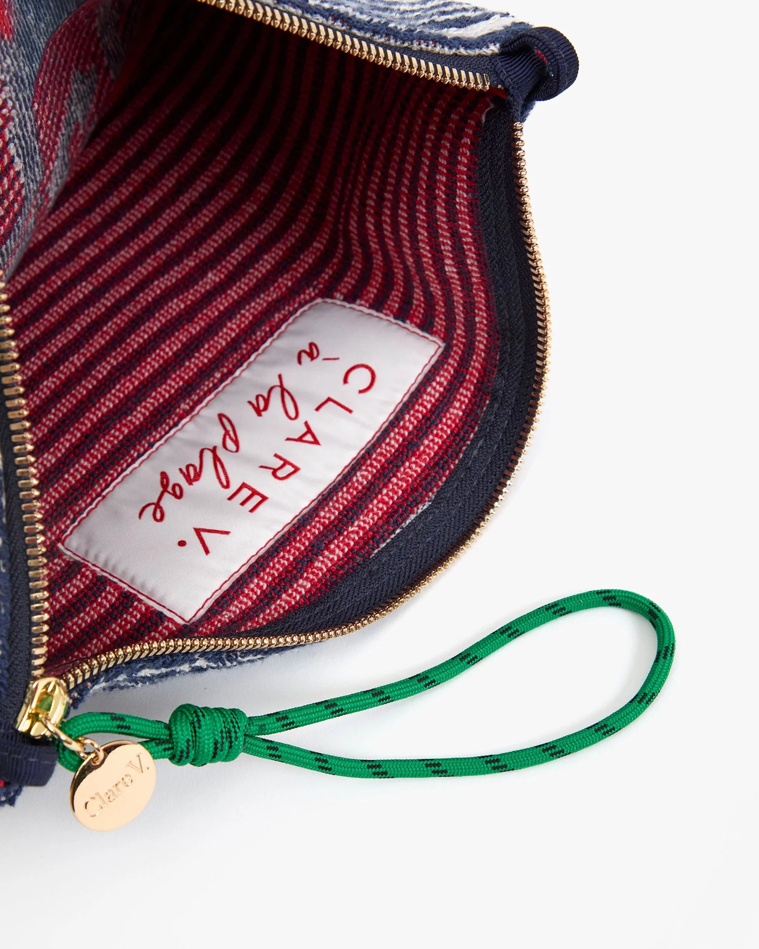 Close-up of a handbag with a visible brand label and green strap.