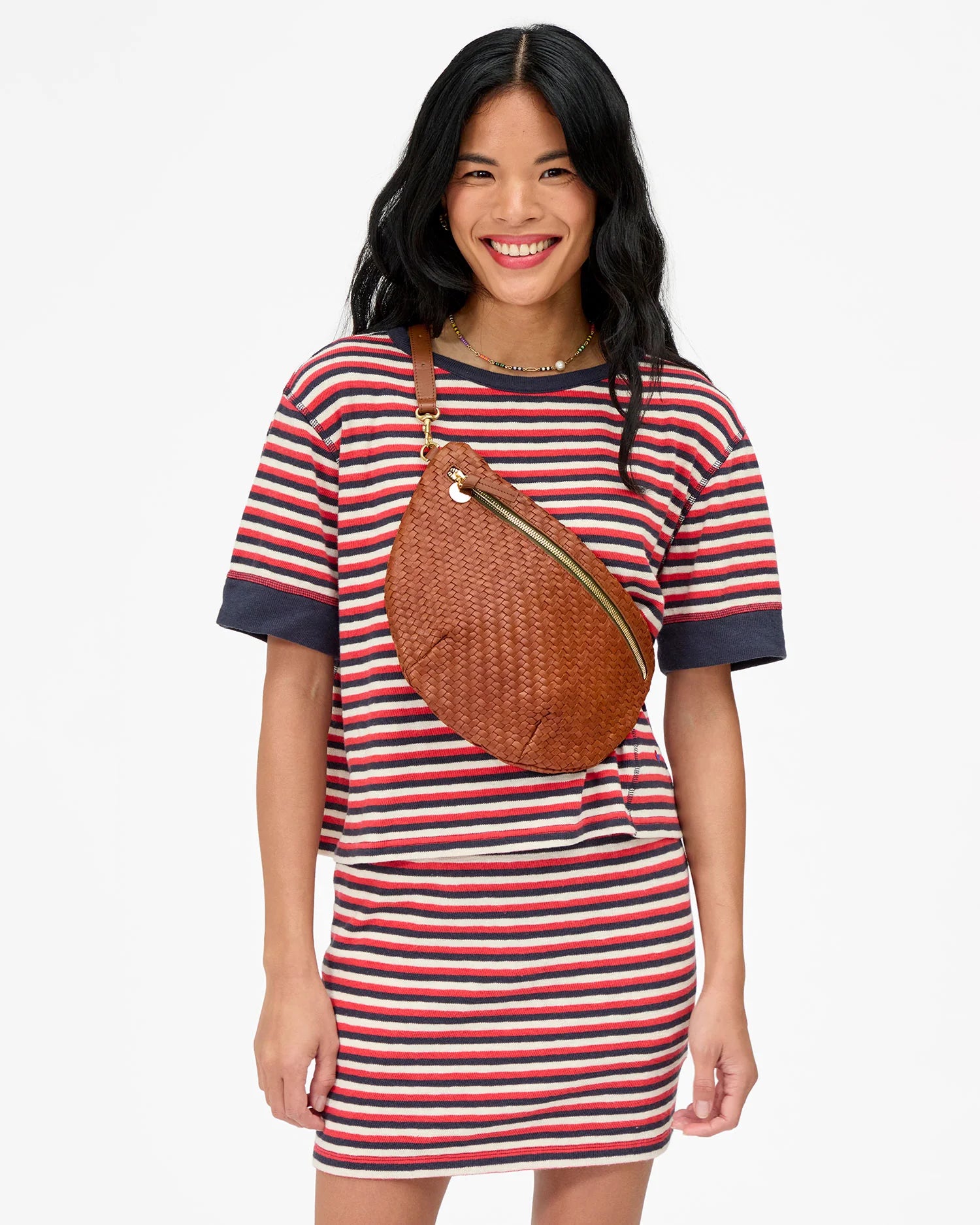 Woman wearing a striped dress with a brown bag on a white background
