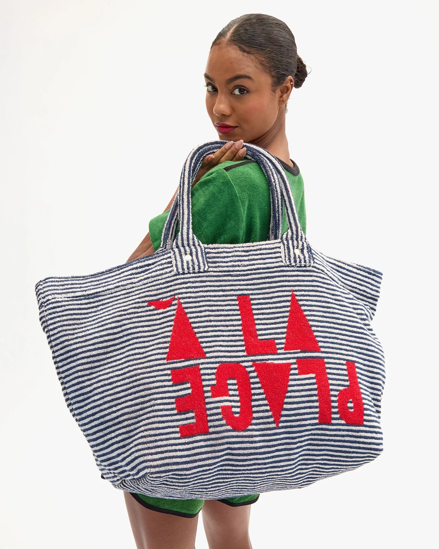 Woman holding a striped tote bag with red text on a white background