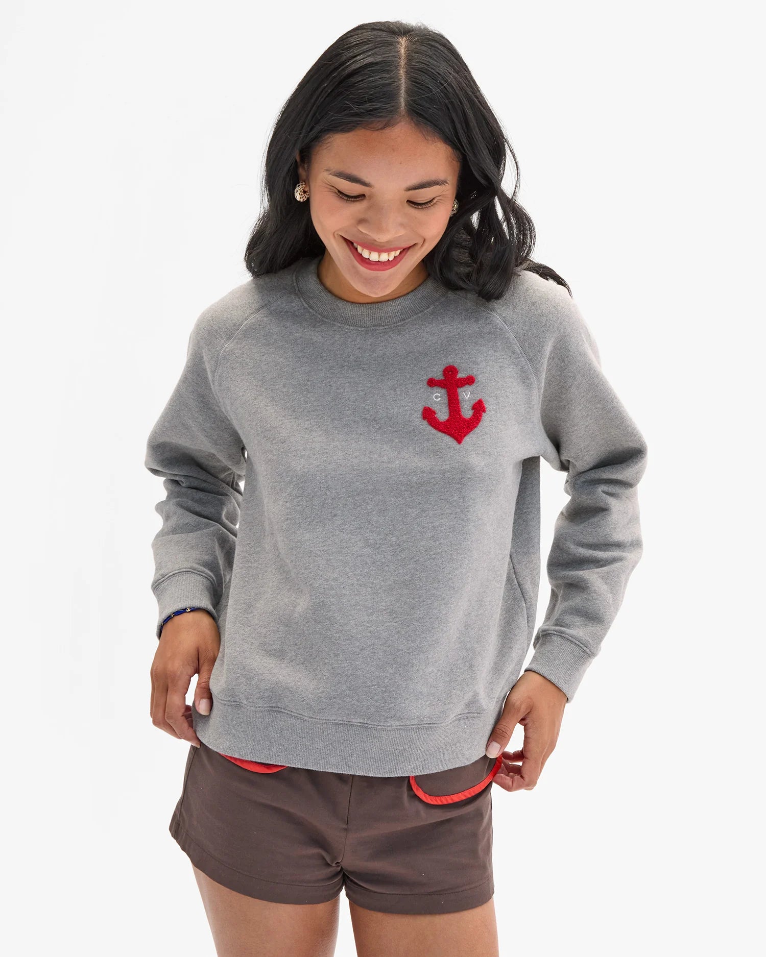 Person wearing a gray sweatshirt with a red anchor design on a white background