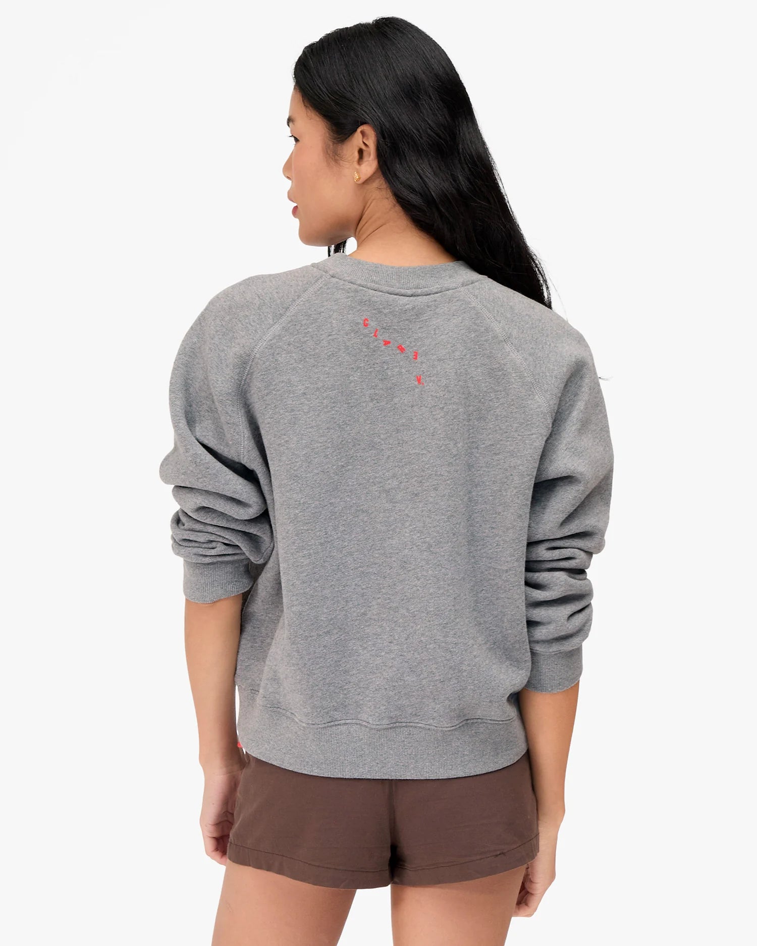 Person wearing a gray sweatshirt with a red design on the back, standing against a white background.