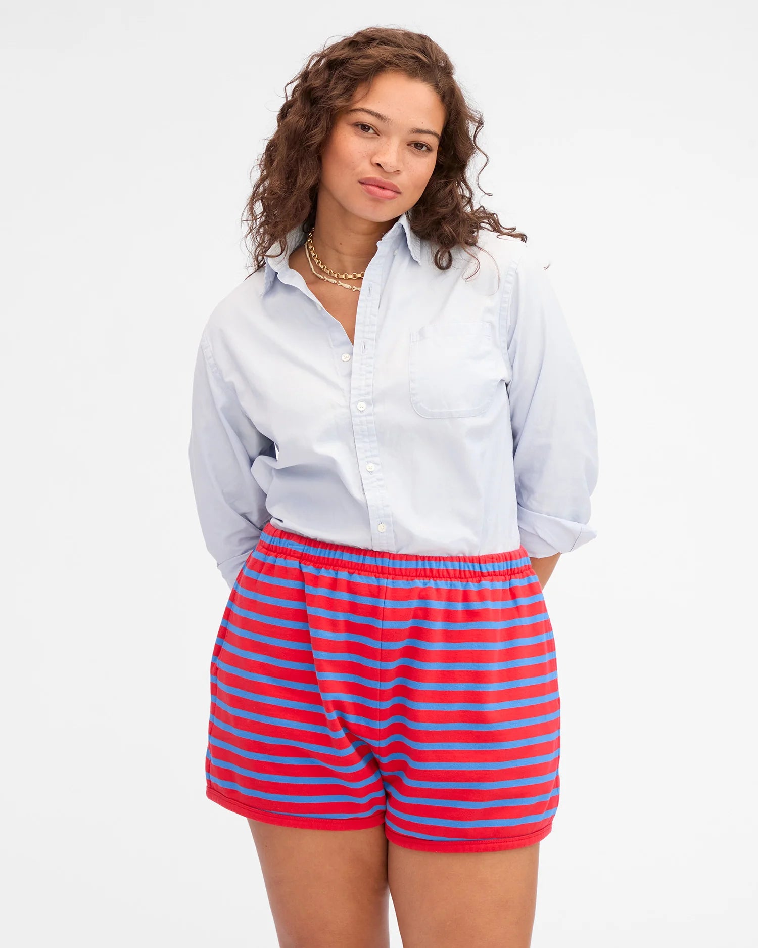 Woman wearing a light blue shirt and red and blue striped shorts on a white background