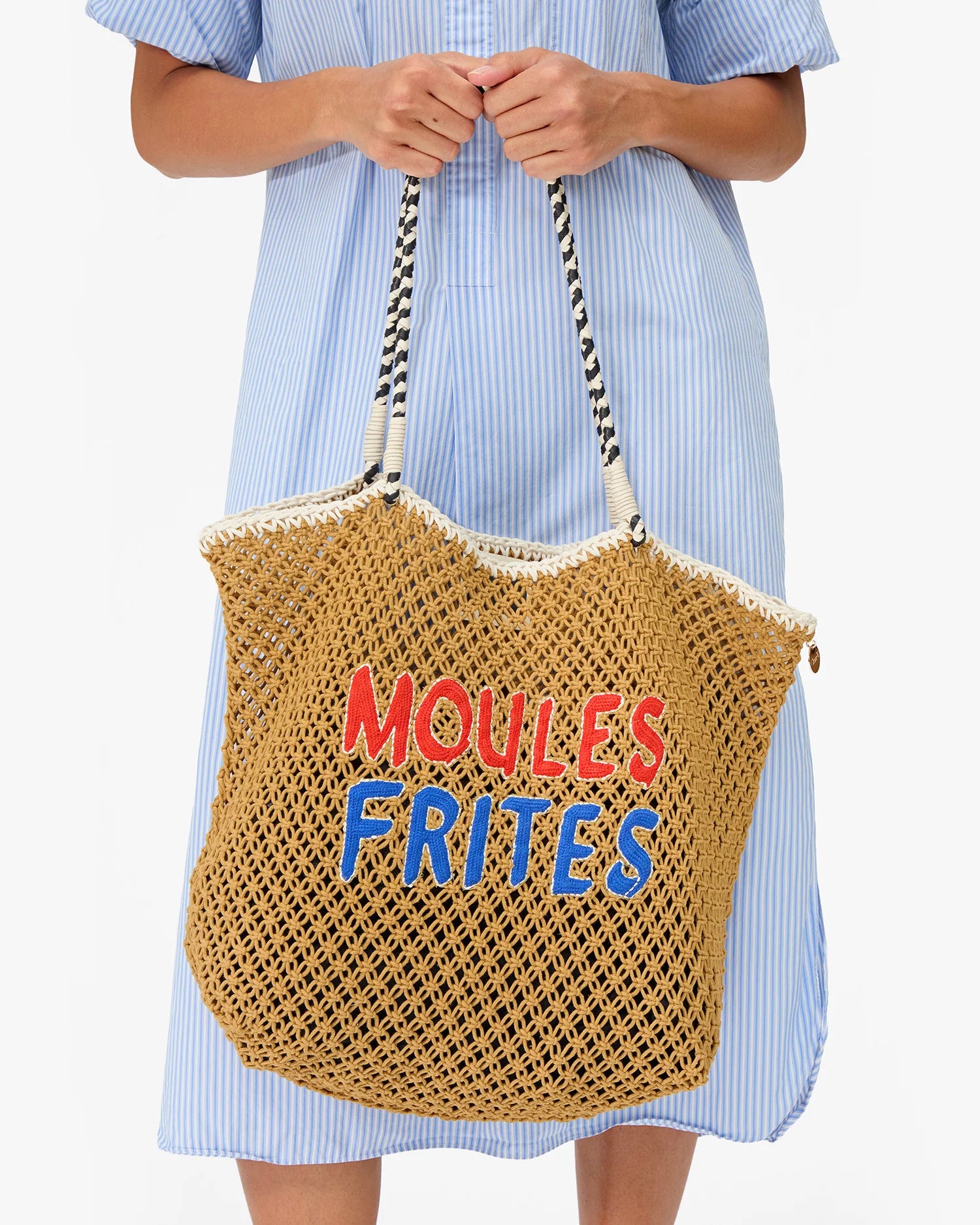 Woven bag with 'MOULES FRIITES' text held by a person wearing a blue dress.
