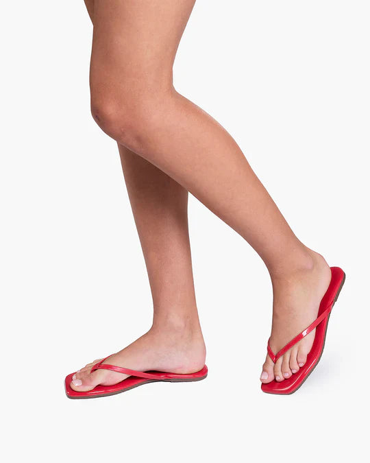 Red flip-flops worn on feet against a white background