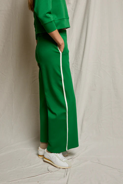 Person wearing a green tracksuit with white stripes on a plain background