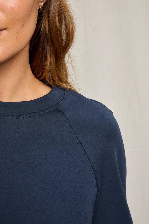 Navy blue long-sleeve top worn by a person against a neutral background